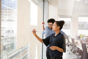 Business people discussing diagram sketches hanging on office window