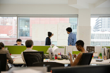 Business people discussing diagram sketches hanging on office window