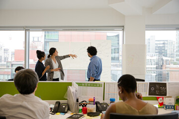 Business people discussing diagram sketches hanging on office window