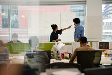 Business people discussing diagram sketches hanging on office window