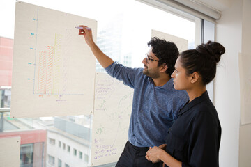 Business people discussing diagram sketches hanging on office window