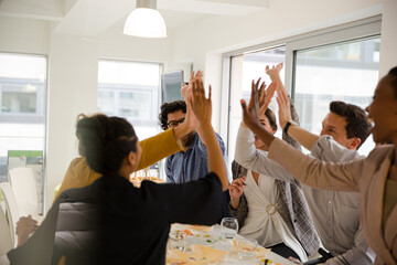 Happy business people touching hands, celebrating success with sushi lunch