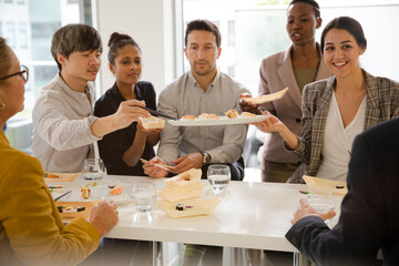 Business people enjoying sushi lunch in conference room