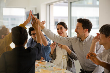 Happy business people touching hands, celebrating success with sushi lunch