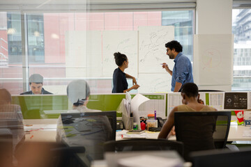 Business people discussing diagram sketches hanging on office window