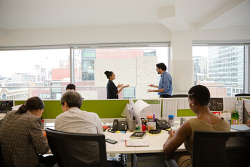 Business people discussing diagram sketches hanging on office window