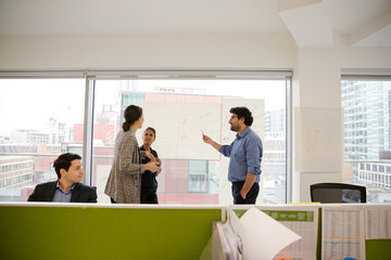 Business people discussing diagram sketches hanging on office window