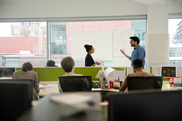 Business people discussing diagram sketches hanging on office window