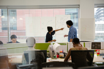 Business people discussing diagram sketches hanging on office window