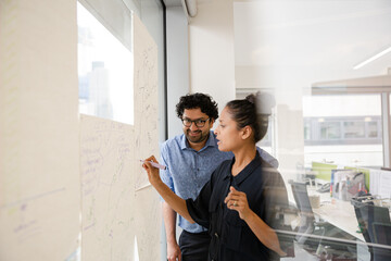 Business people discussing diagram sketches hanging on office window