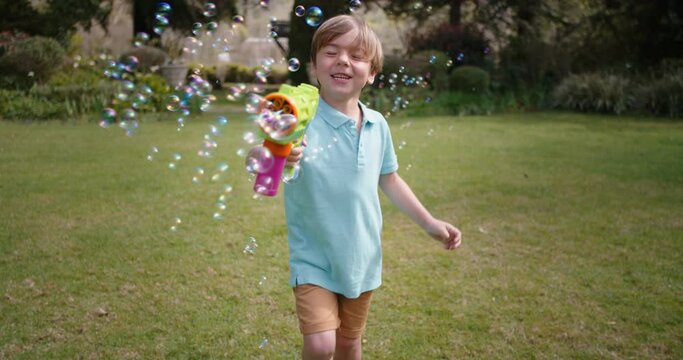 happy little boy blowing soap bubbles playing in sunny garden running with toy gun enjoying fun game funny playful child enjoying summer 4k