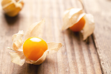 Three physalis Peruvian fruits on a wooden background. 