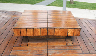 A bench in a square-shaped public park. Wooden panels. A place of rest and reflection.