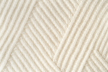 Pastel knitted fabric with visible geometric knitted pattern. Fall and winter concept. Flat lay style. Close up. Copy space.