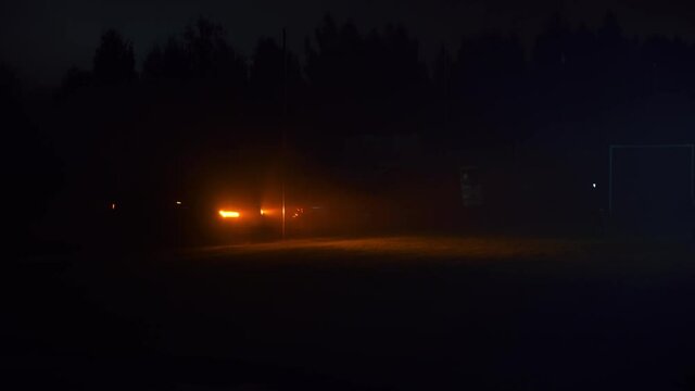 Car headlights glow orange in the dark outside. Blinking alarm light. Cinematic concept