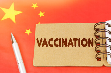 On the flag of China lies a notebook with the inscription - VACCINATION