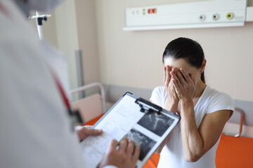 Doctor holding documents in front of crying patient in clinic