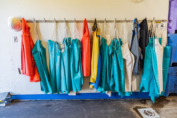 Colorful waterproof aprons hanging on hooks.