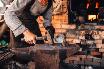 A male blacksmith forges by hand in a forge on a steel anvil - an old craft