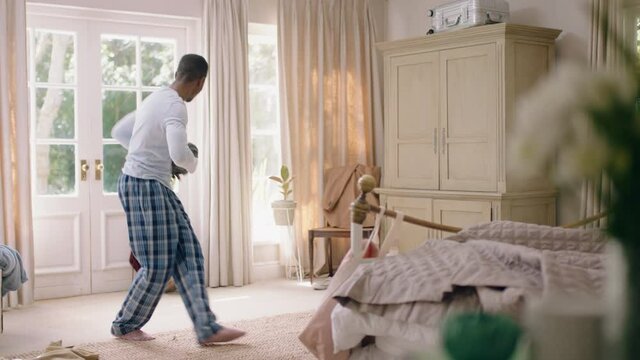 funny african american man dancing in bedroom having fun celebrating feeling positive enjoying successful lifestyle doing silly dance at home on weekend morning wearing pajamas