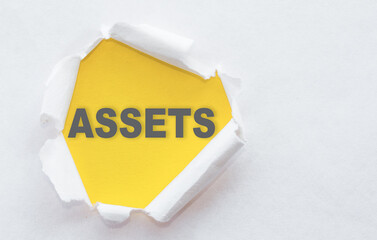 Top view of white torn paper and the text ASSETS on a yellow background.