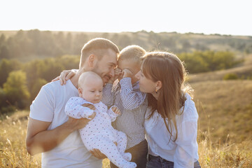 Fototapeta premium family in light outfits with small children posing against the backdrop of nature