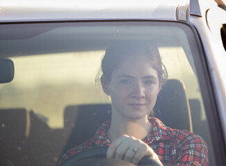 Portrait of pretty young redhead woman driving car.