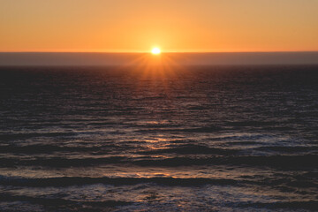 Obraz premium Panoramic view of the pacific ocean and beautiful sunset in the horizon with sun and rays in the center 