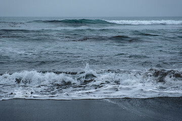 Panoramic view of the pacific ocean with waves, the horizon with cloudy sky and the shore and beach