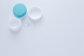 A container for lenses and two contact lenses lie on the side on a white background with space for text. top view, flat lay, copy space, isolate