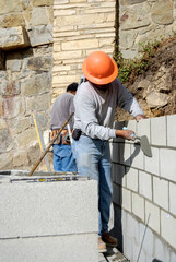 Mason crew raising a concrete block retaining wall