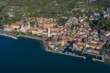 Obraz premium Brenzone sul Garda, Italy, September 2021, aerial view of Castelletto di Brenzone at Garda (Lake), showing the coastline with roads and the tranquil coastal villages with a small harbor (port)
