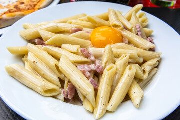 Pasta penne ala carbonara with egg yolk and ham