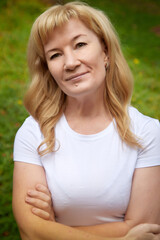 Portrait of an middle-aged woman with a green background in a park or forest in nature