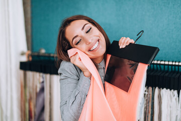 Young woman designer chooses fabrics for curtains in textile show room.