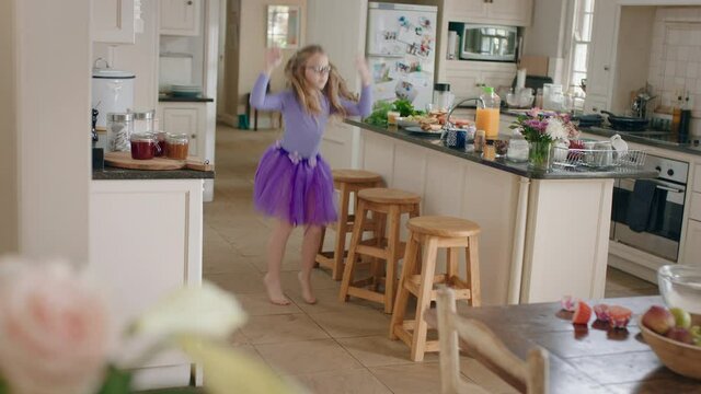 happy ballerina girl dancing in kitchen wearing purple tutu having fun performing funny dance moves enjoying weekend celebration at home
