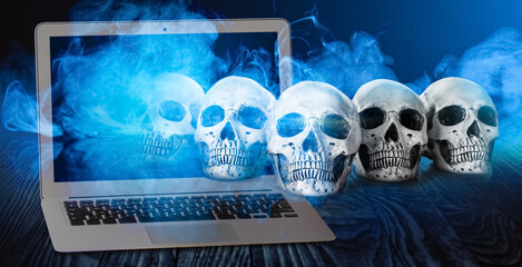 Modern laptop and human skulls on dark background