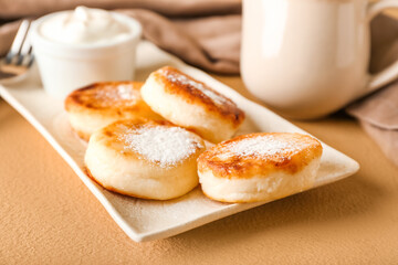Plate with tasty cottage cheese pancakes on table