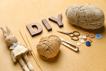 Composition with word DIY and knitting supplies on color background