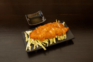 Chinese recipe for lemon chicken with chicken breast fillet coated in flour, egg and breadcrumbs on a bed of green cabbage