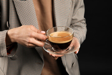 Woman drinking tasty coffee on dark background, closeup