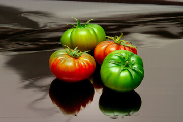 A kilo of ripe raf tomatoes on a black surface in which they are reflected - obrazy, fototapety, plakaty