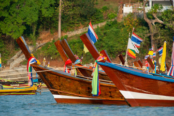 Fototapeta na wymiar Bows of cheerful and colorful long tail boats moored on a Thai beach
