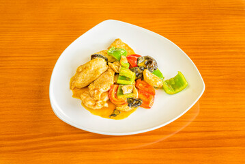 chicken curry recipe with Chinese mushrooms and vegetables sautéed in the wok on a cherry-colored table