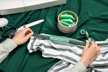 Woman measuring clothes on fabric background