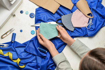 Woman with medical mask and fabric on light background