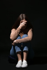 Scared young woman on dark background. Concept of harassment