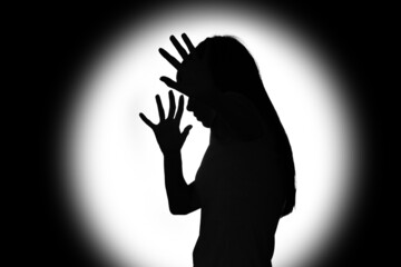 Silhouette of scared young woman on dark background. Concept of harassment