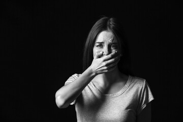 Scared young woman on dark background. Concept of harassment