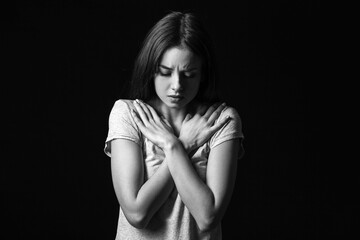 Scared young woman on dark background. Concept of harassment